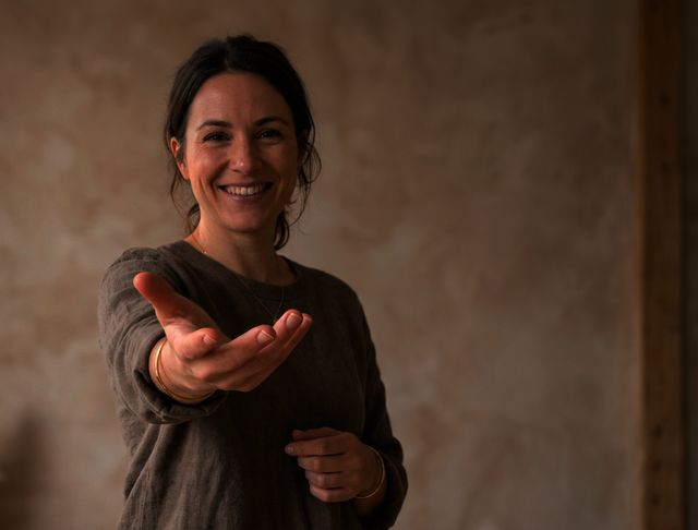 Une femme souriante tend la main, dans une lumière chaude